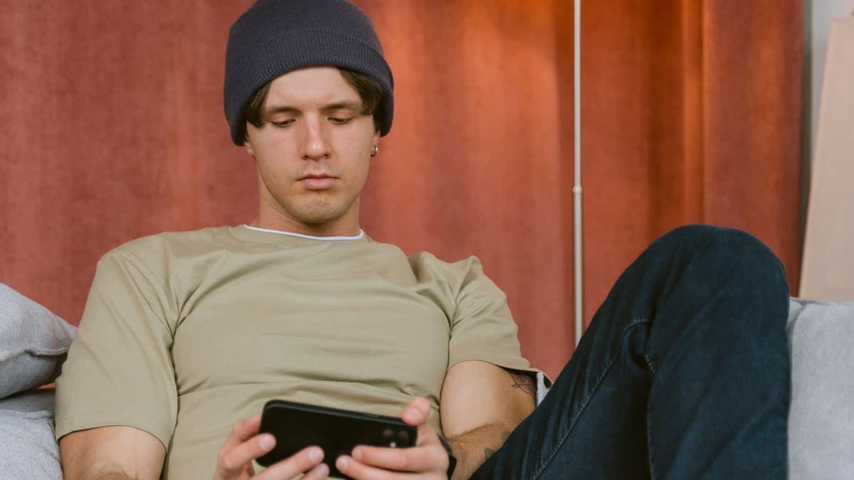 Person sitting on a sofa holding a mobile phone to configure a streaming app