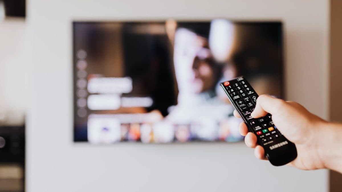 Person pressing a button on a remote control while troubleshooting a streaming device