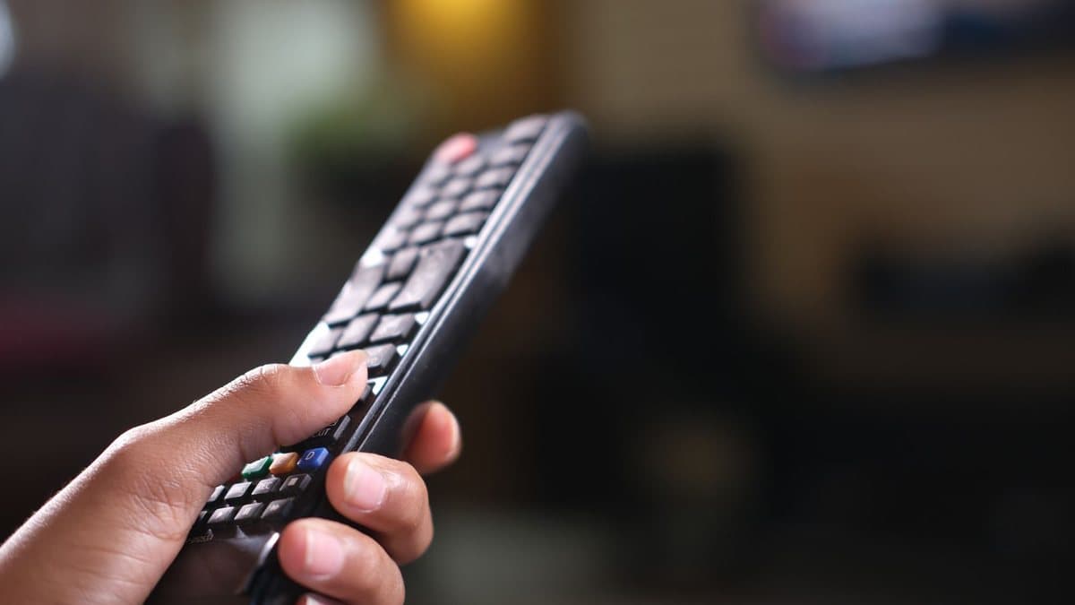 Close-up of a hand holding a black remote control