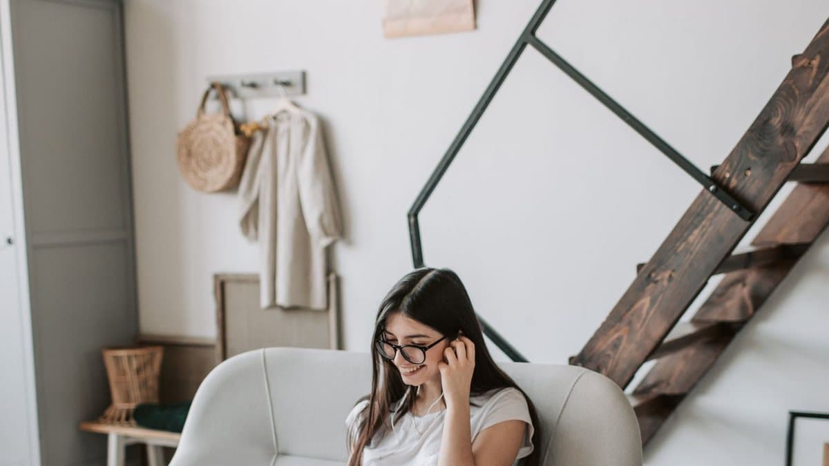 Person relaxing in a cozy living room while browsing on a laptop