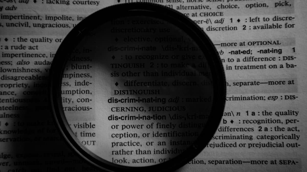 Magnifying glass over dictionary text, representing a close look at a spelling difference
